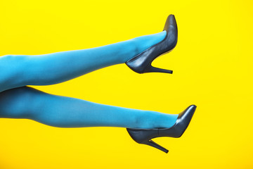 Young woman in stylish high heels on color background