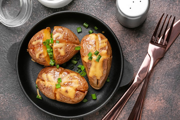 Frying pan with tasty baked potato on table