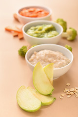 Bowls with healthy baby food on color background