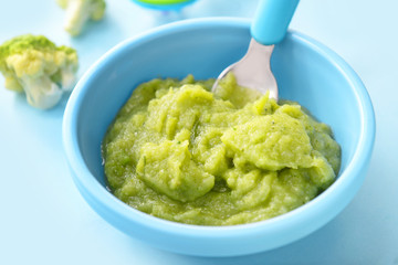 Bowl with healthy baby food on color background, closeup