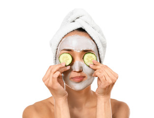 Asian woman with facial mask and cucumber slices on white background