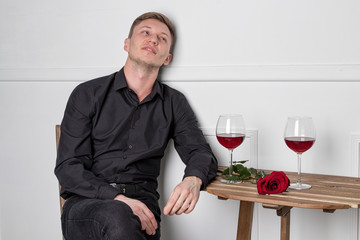 Young handsome man sitting by table in cafe while waiting for his girlfriend
