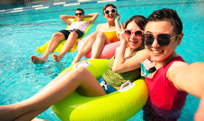 happy young friends taking selfie at the swimming pool