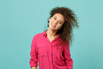 Fototapeta premium Portrait of attractive african girl in casual clothes standing with flowing hair isolated on blue turquoise wall background in studio. People sincere emotions, lifestyle concept. Mock up copy space.