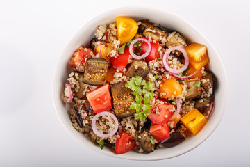 Quinoa salad with roasted eggplant, fresh tomatoes and red onion.   Vegan or vegetarian food. Healthy salad in bowl served on white table. Top view, close-up.