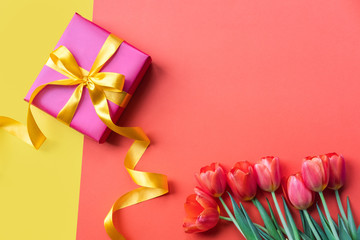 Present and flowers on color background. Holidays concept. Copy spase