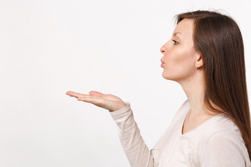 Side view of attractive pretty tender young woman in light clothes blowing sending air kiss...