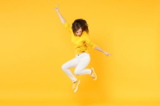 Cheerful Funny Young Woman In Summer Casual Clothes Jumping And Spreading Hands Isolated On Yellow Orange Wall Background In Studio. People Sincere Emotions, Lifestyle Concept. Mock Up Copy Space.