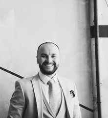 portrait of cheerful middle aged man with beard standing against wall and smiling