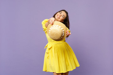 Portrait of pretty stunning young woman in yellow dress holding summer hat looking camera isolated on pastel violet background in studio. People sincere emotions lifestyle concept. Mock up copy space.