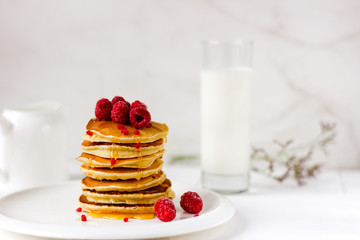 Tall stack of pancakes with honey and raspberries on white plate. Breakfast for the whole family 