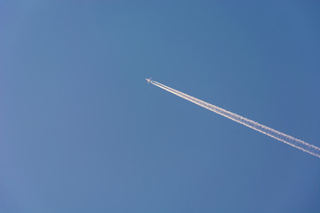 A fuzzy high-flying passenger plane and white streaks on a sky