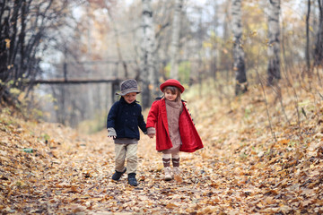Fototapeta premium Children walk in autumn forest, kick leaves,