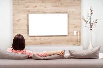 Back view of beautiful young woman resting in luxury appartments, sitting on the sofa and watching...