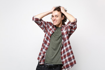 Portrait of irritated nervous young man in casual clothes looking camera, putting hands on head isolated on white background in studio. People sincere emotions, lifestyle concept. Mock up copy space.