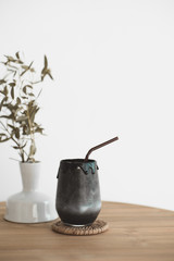 Black beverage drink made from charcoal and milk on vintage style wood table with dry plant leaf decoration pot.