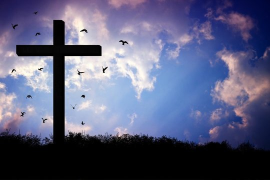 Wooden Crucifix of Jesus on The Mountain with Flying Birds and Beautiful Sky Background for catholic and Christian Religion Concepts.