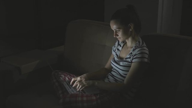 European brunette woman communicates on the Internet through a computer in the evening