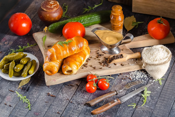 pies, loaf bread, dough on a wooden vintage cutting board old rustic, mustard sauce-dish, tomato,...