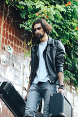 Street musician holding a case with a guitar and amplifier. Descends into the underground passage. Vagrant lifestyle. Playing to make money a living. Unemployed musician. Future rock star.
