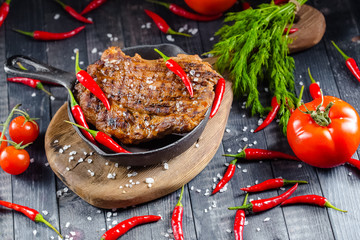 grilled kebab grilled meat steak lies in an iron frying pan, on a wooden vintage old board rustic,...