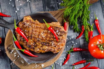 grilled kebab grilled meat steak lies in an iron frying pan, on a wooden vintage old board rustic,...