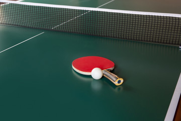 ping-pong racket and a ball on a green table. ping-pong net.