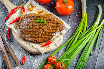 grilled kebab grilled meat steak lies on a wooden vintage old board rustic, chili, with tomatoes,...