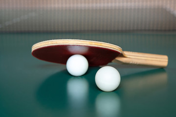 ping-pong racket and a  two balls on a green table. ping-pong net.