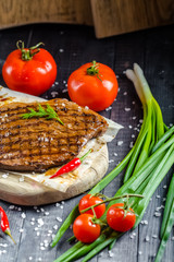 grilled kebab grilled meat steak lies on a wooden vintage old board rustic, chili, with tomatoes,...