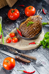 grilled kebab grilled meat steak lies in an iron frying pan, on a wooden vintage old board rustic,...
