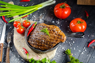 grilled kebab grilled meat steak lies in an iron frying pan, on a wooden vintage old board rustic,...