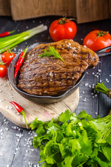 grilled kebab grilled meat steak lies in an iron frying pan, on a wooden vintage old board rustic,...
