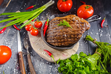 grilled kebab grilled meat steak lies in an iron frying pan, on a wooden vintage old board rustic,...