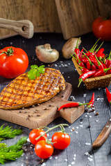 grilled kebab grilled meat steak lies on a wooden vintage old board rustic, chili, with tomatoes,...