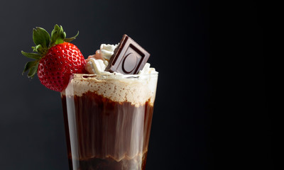 Chocolate drink with whipped cream, strawberry and pieces of black chocolate.