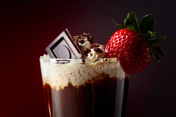 Chocolate drink with whipped cream, strawberry and pieces of black chocolate.