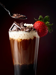 Chocolate drink with whipped cream, strawberry and pieces of black chocolate.