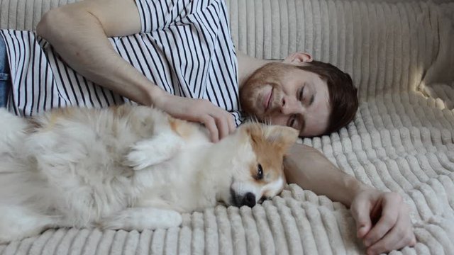 young man is lying on a bed with his sleeping dog.