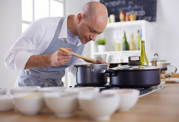 Handsome man is cooking on kitchen and smiling
