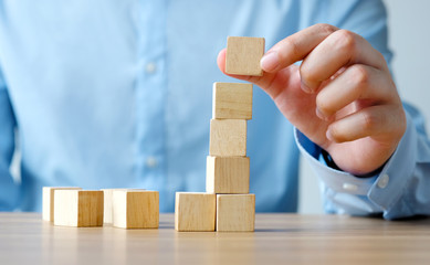 Hand holding blank wooden cubes on wooden table, business concept background, mock up, template