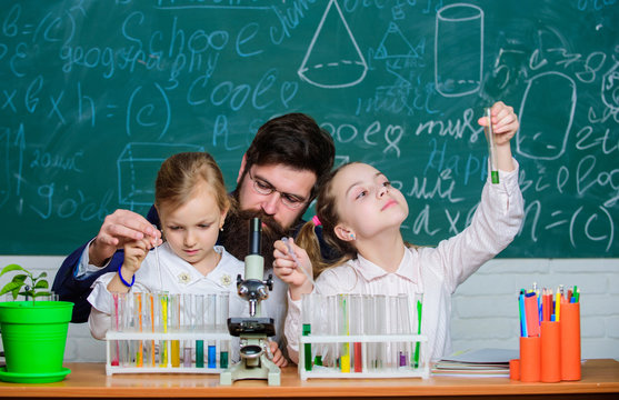 Prove it. Little girls performing experiment under teacher supervision. Small school children holding test tubes for laboratory experiment. Demonstration and experiment