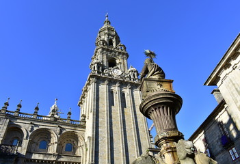 Fototapeta na wymiar Cathedral, romanesque Platerias facade and baroque clock tower with stone horses fountain and blue sky. Santiago de Compostela, Spain.