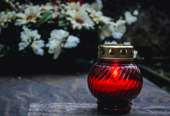 Single red candle on a grave on the cemetery in Warsaw, Poland
