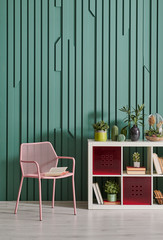 Green room, pink metal chair and white bookshelf with home object.