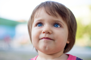 Portrait of a funny little girl on a walk. 1.5 year old girl's face close up. Blue eyes of a child, Slavic type of face.