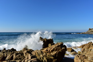 Wild waves breaking against the rocks. Blue sky, sunny day, Castro de Baroña, Galicia, Spain.