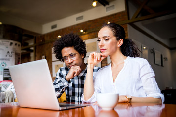 Multiethnic business team meeting at cafe, working using laptop