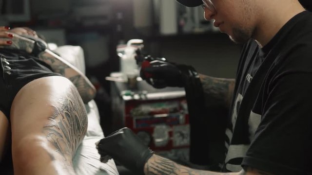 Professional artist making tattoo in salon. Close-up view of male hand making tattoo closeup macro