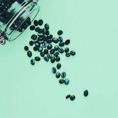 Arabica coffee beans spill out of a glass jar on monophonic background, close-up, day, art, minimal, modern design